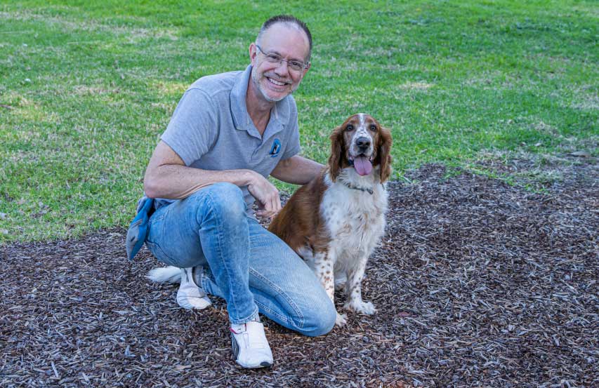 Dog trainer Mark Ehrman kneeling with relaxed dog